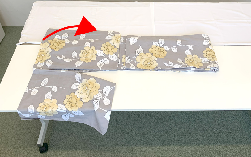 エリを持って半分に折り返します。